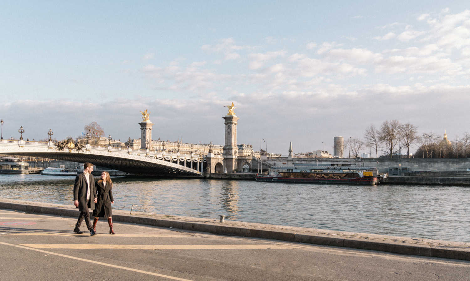 newly engaged couple walk along seine river in paris