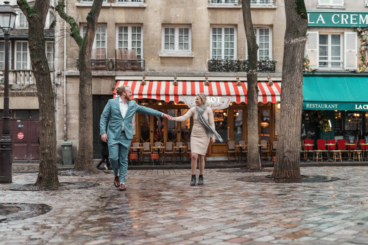 newly engaged couple walk in charming square in montmartre paris