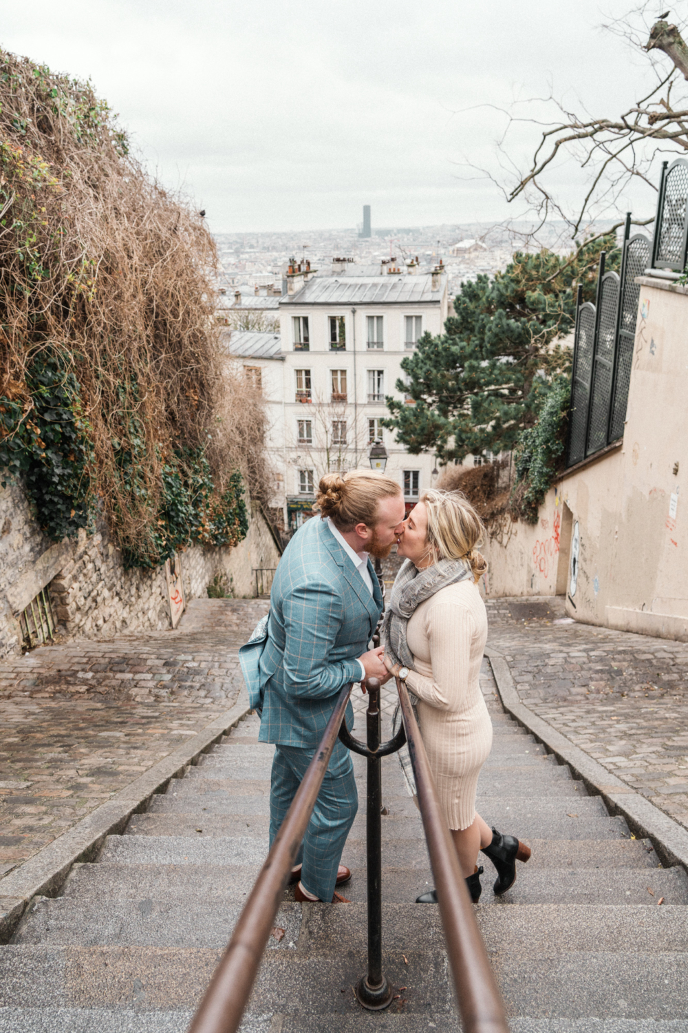 newly engaged couple kiss on staircase in montmartre in paris