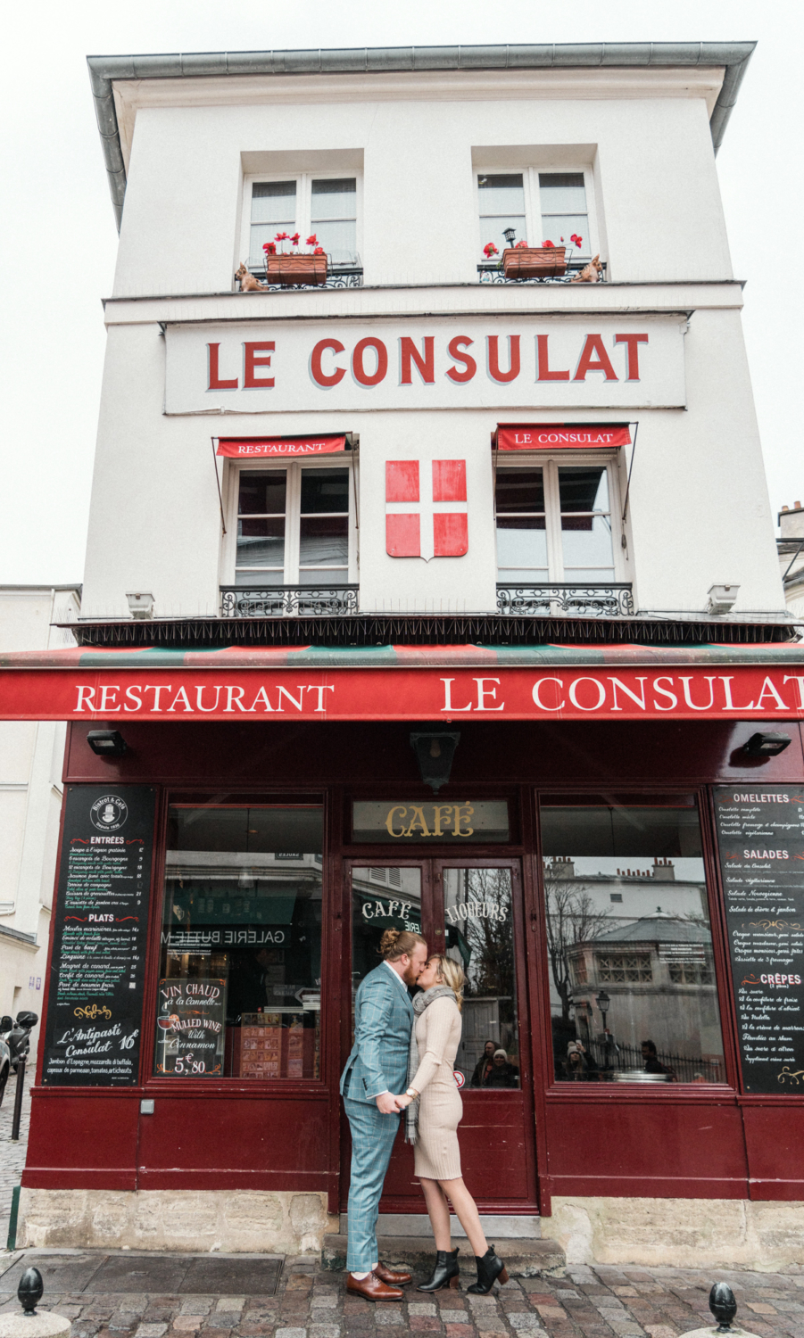 newly engaged couple kiss at le consulat restaurant in paris