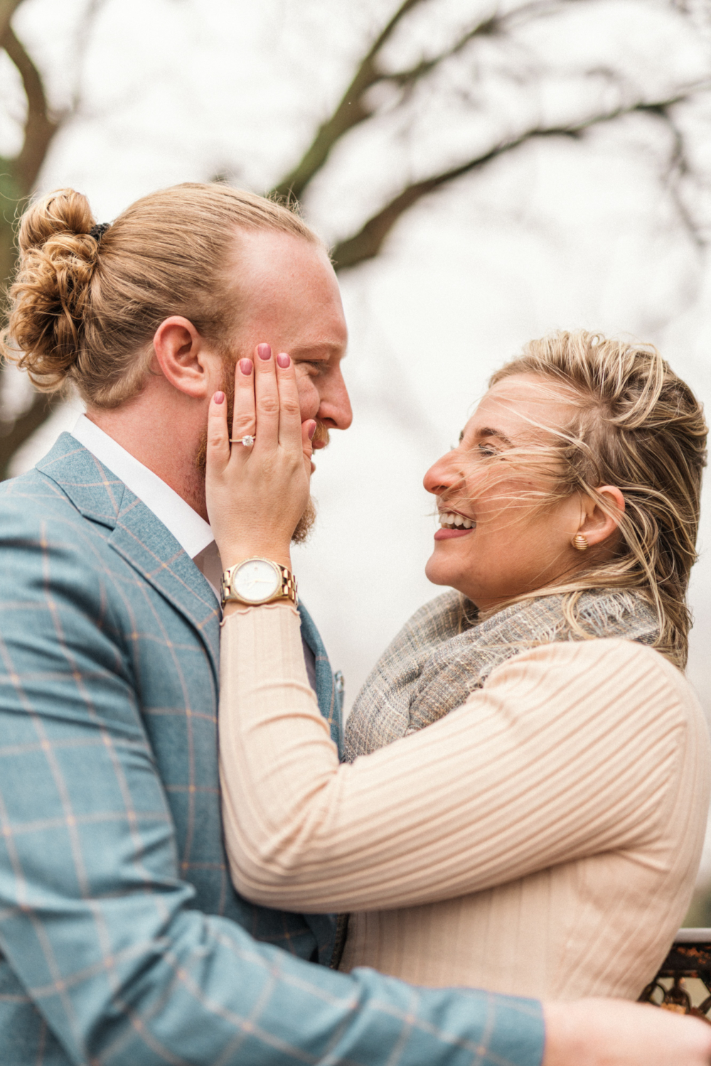 newly engaged couple laugh with each other in the wind in paris