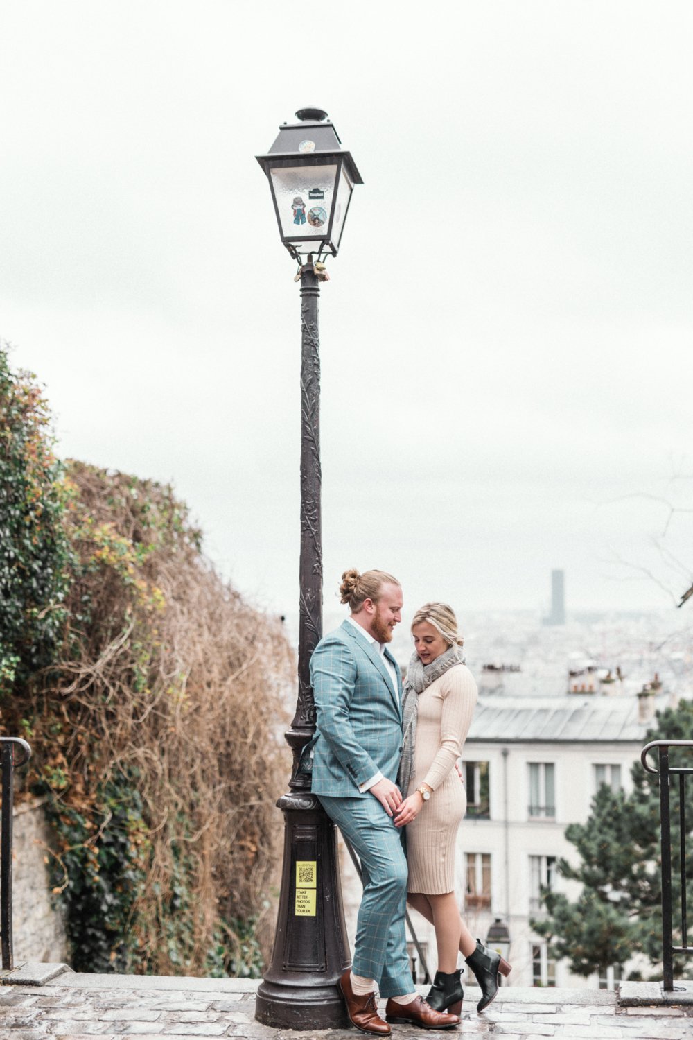 newly engaged couple pose at top of hill in montmartre paris