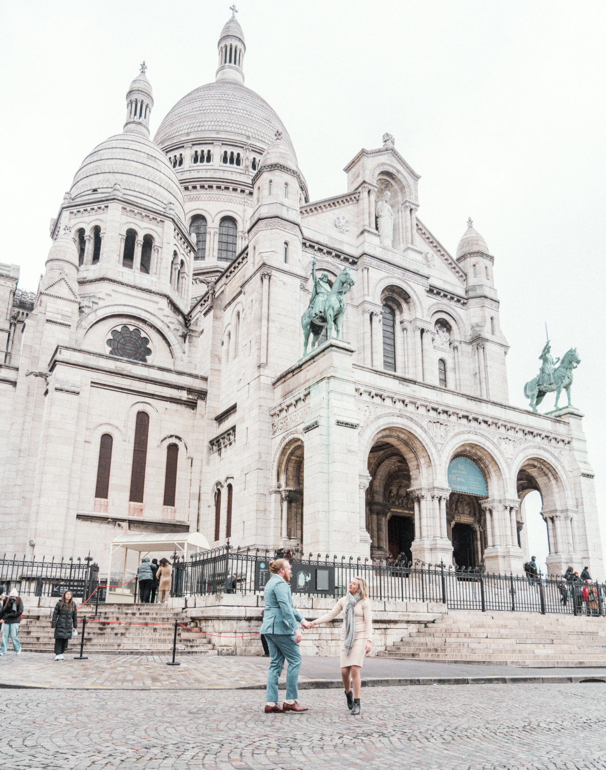 newly engaged couple hold hands outside sacre coeur basilica in paris