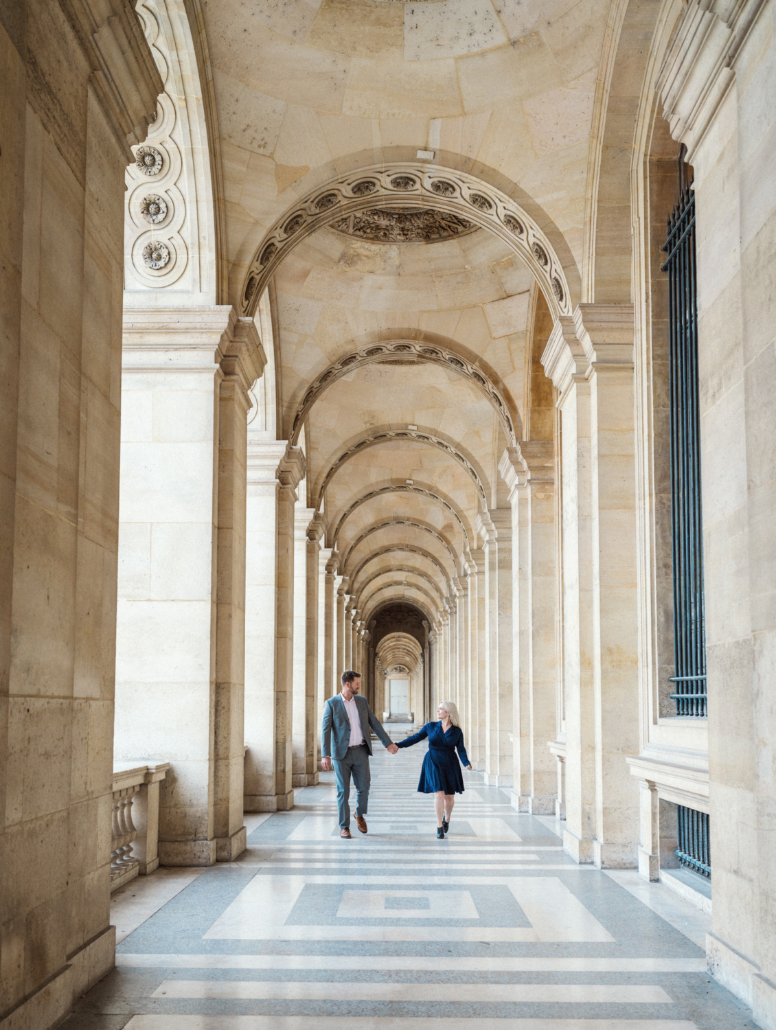 engaged couple walk in corridor at the louvre in paris