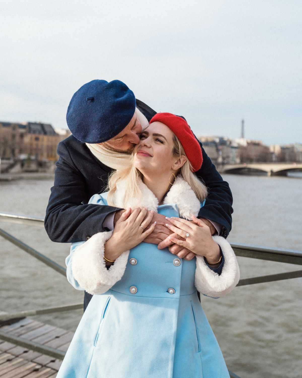 man wearing beret kisses woman wearing beret on side of face in paris