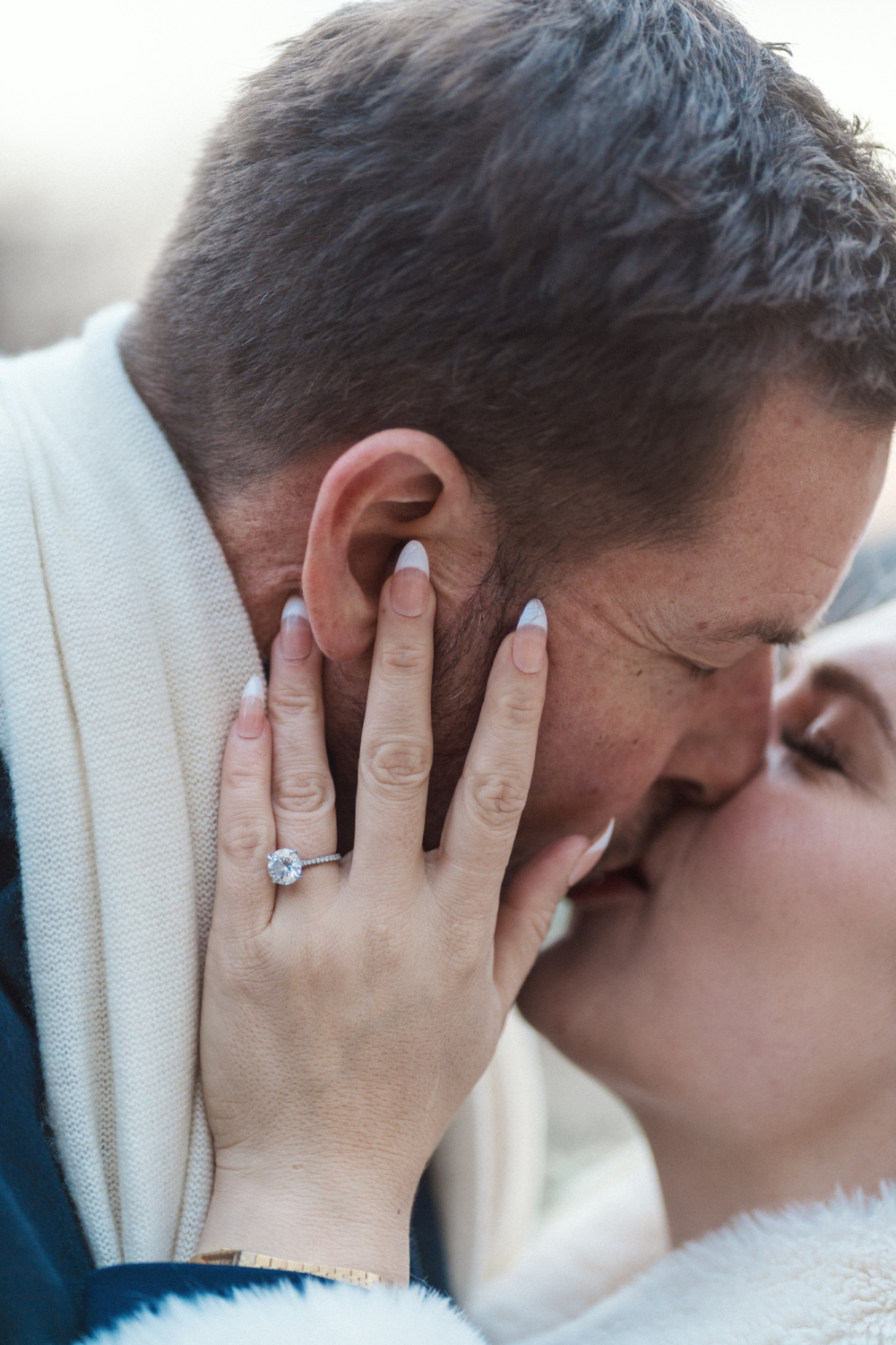man and woman kiss with view of engagement ring
