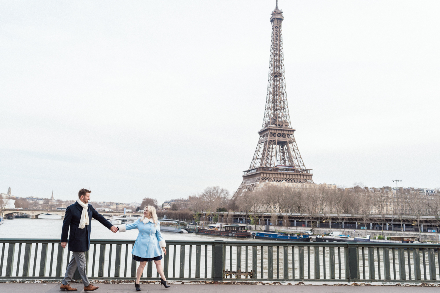 man and woman hold hands walking in paris with view of eiffel tower