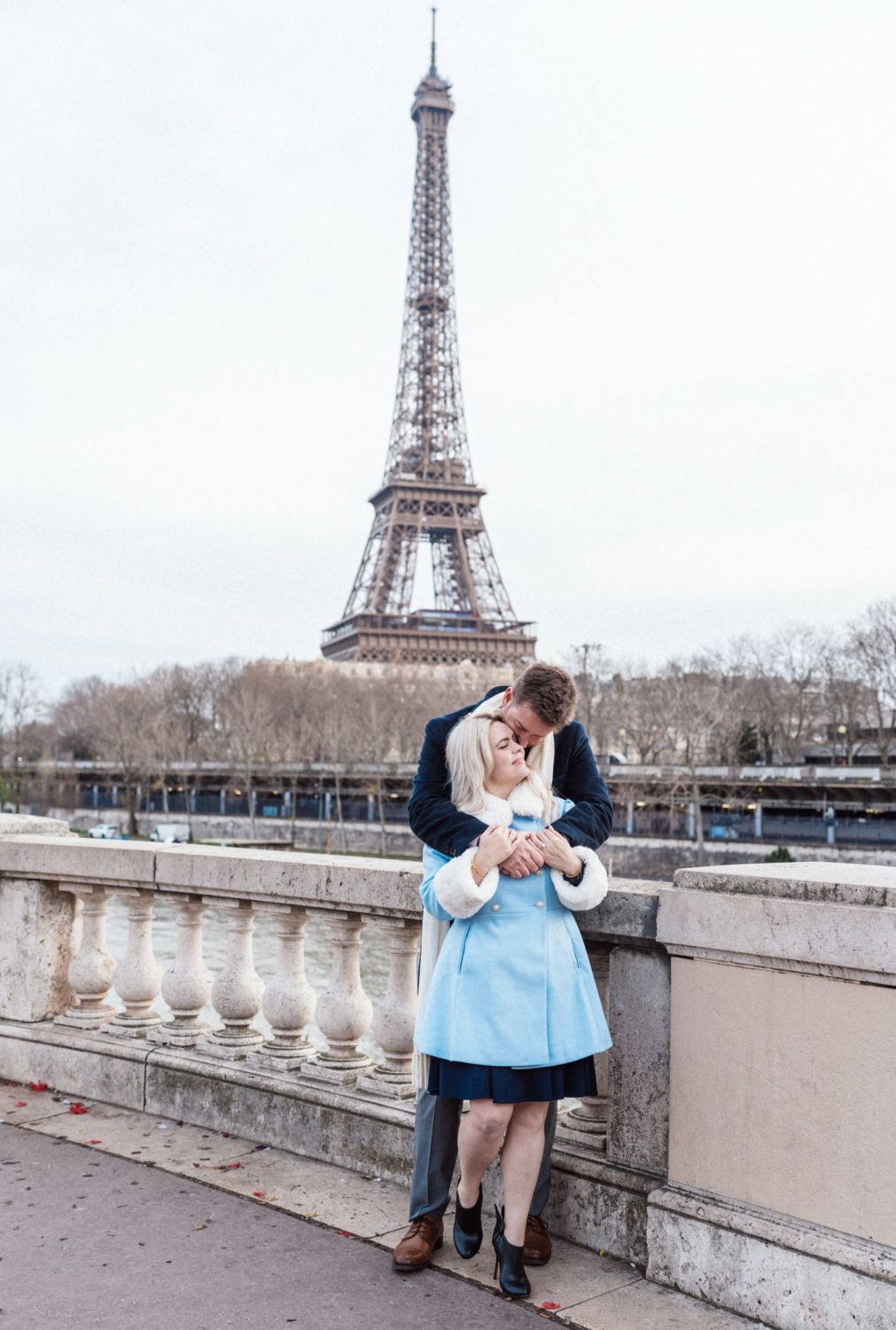 man wraps arms around woman in front of the eiffel tower paris