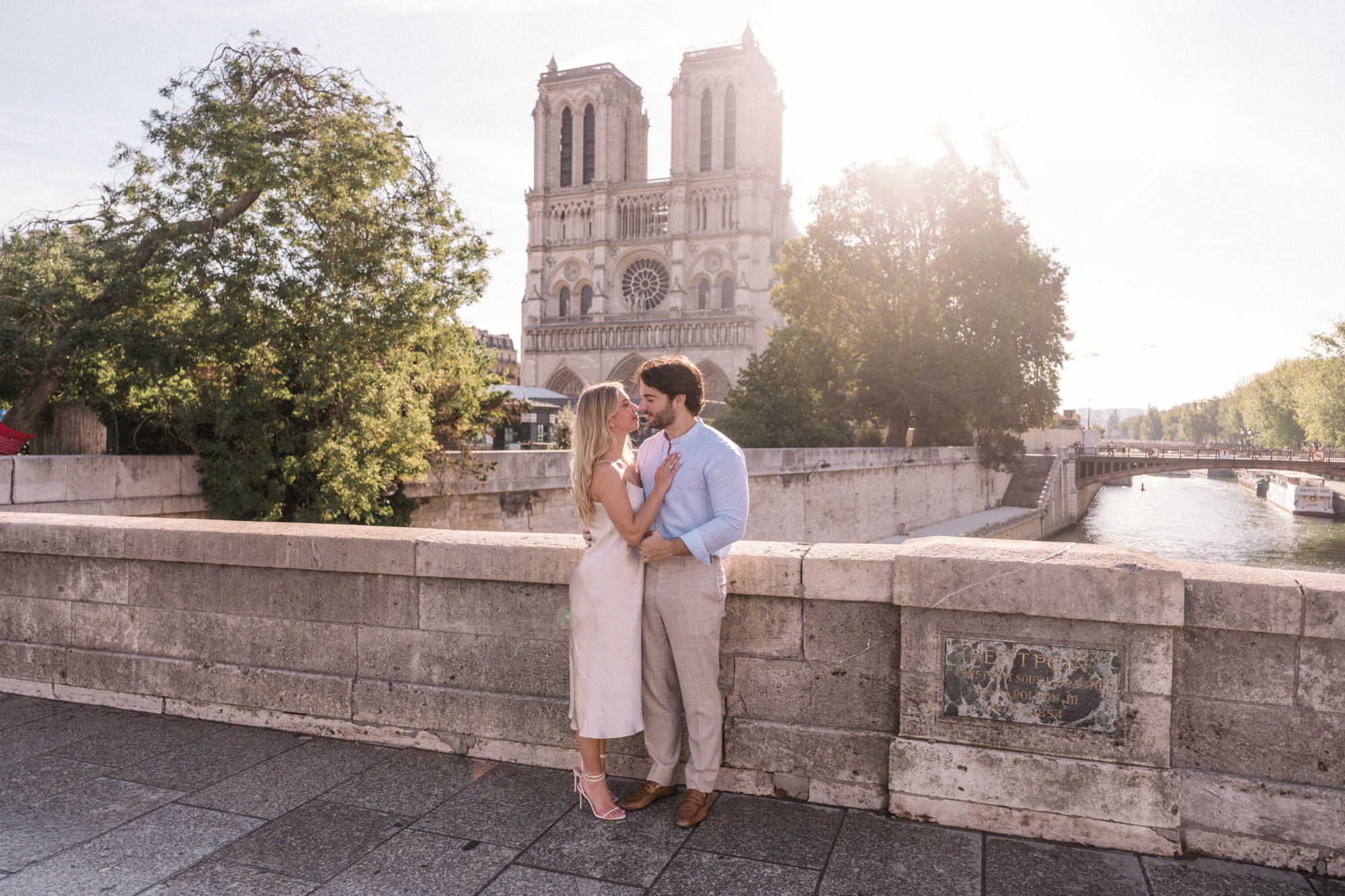 engaged young couple embrace with view of notre dame cathedral in paris