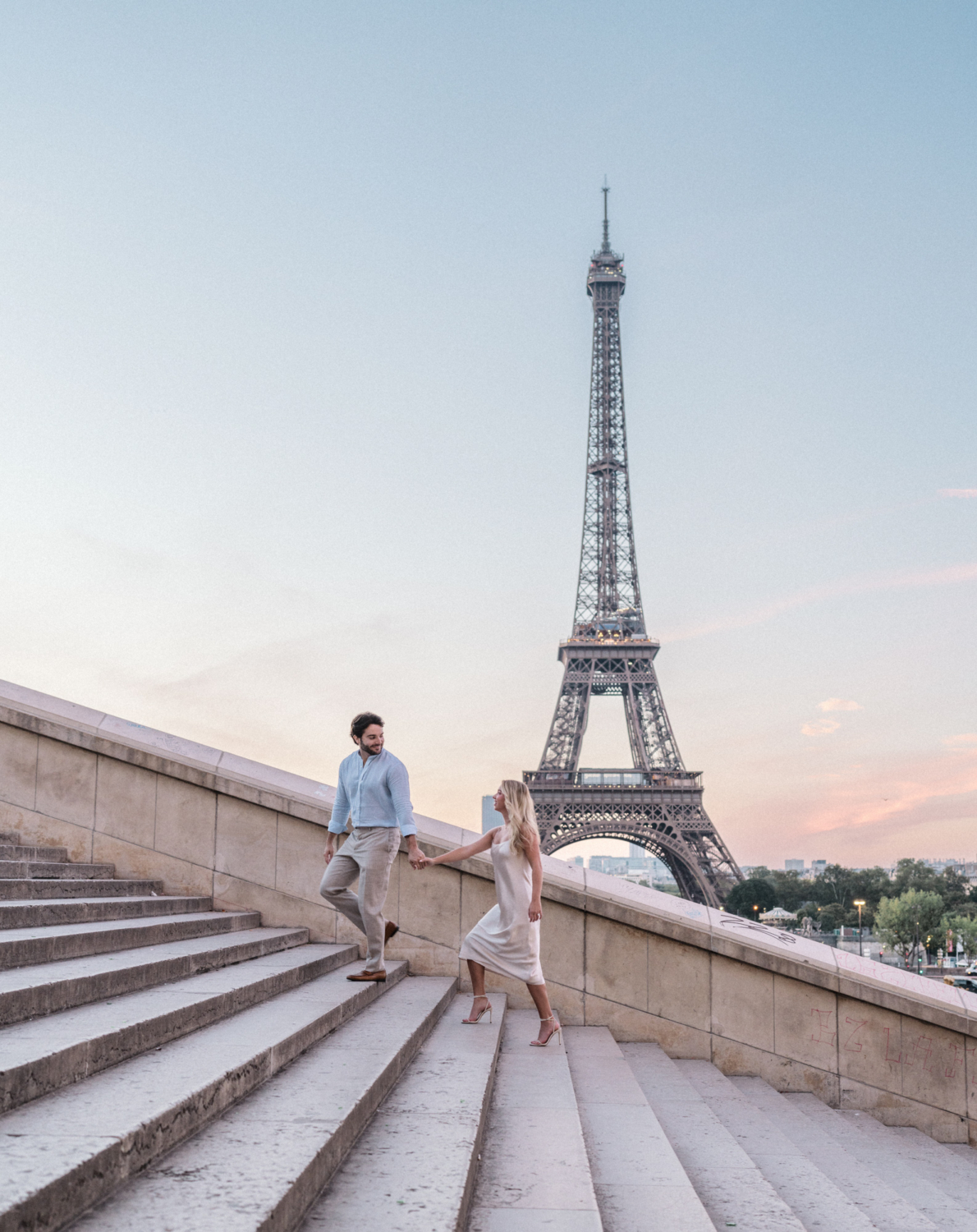 engaged young couple climb staircase at sunrise in paris