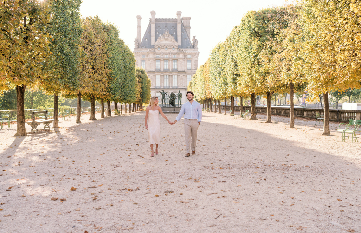 engaged young couple walk together in the tuileries gardens in paris