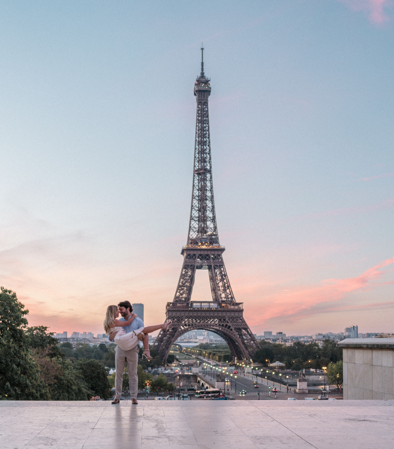 man carries woman at the eiffel tower at sunrise in paris