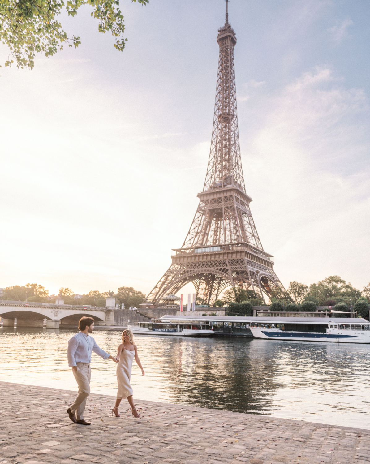 engaged young couple walk holding hands at the eiffel tower in paris