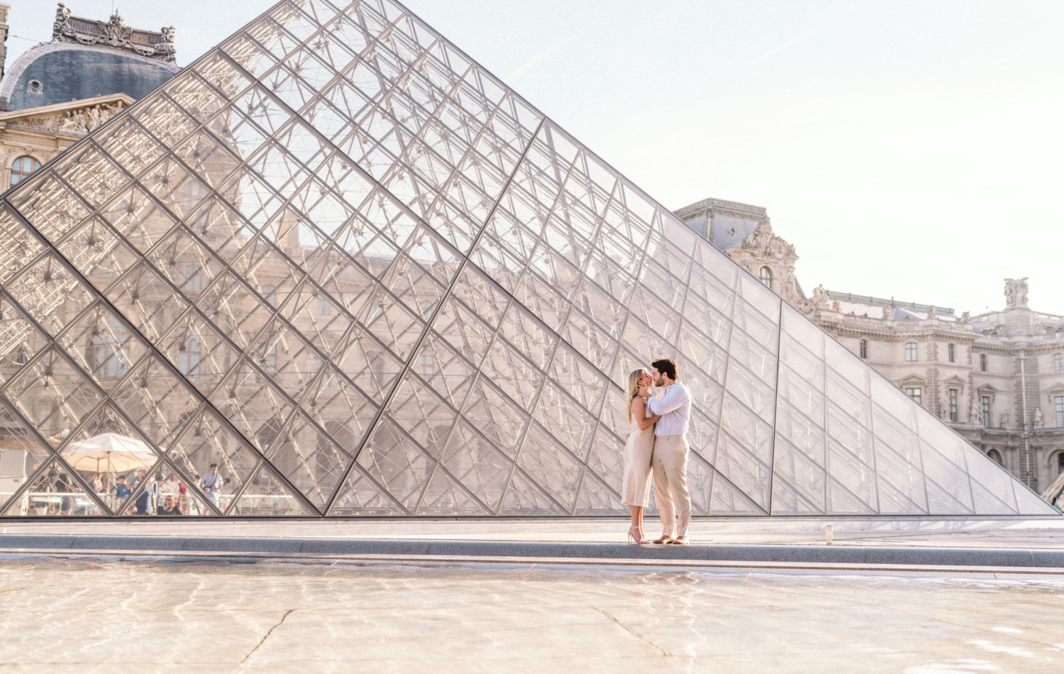 engaged young couple embrace passionately at the louvre pyramid in paris