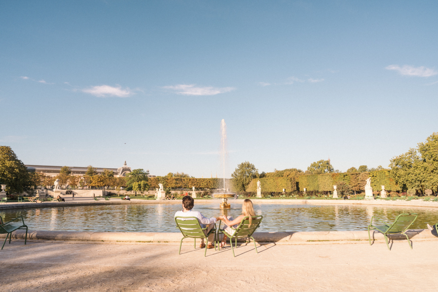 engaged young couple sit in the tuileries gardens in paris