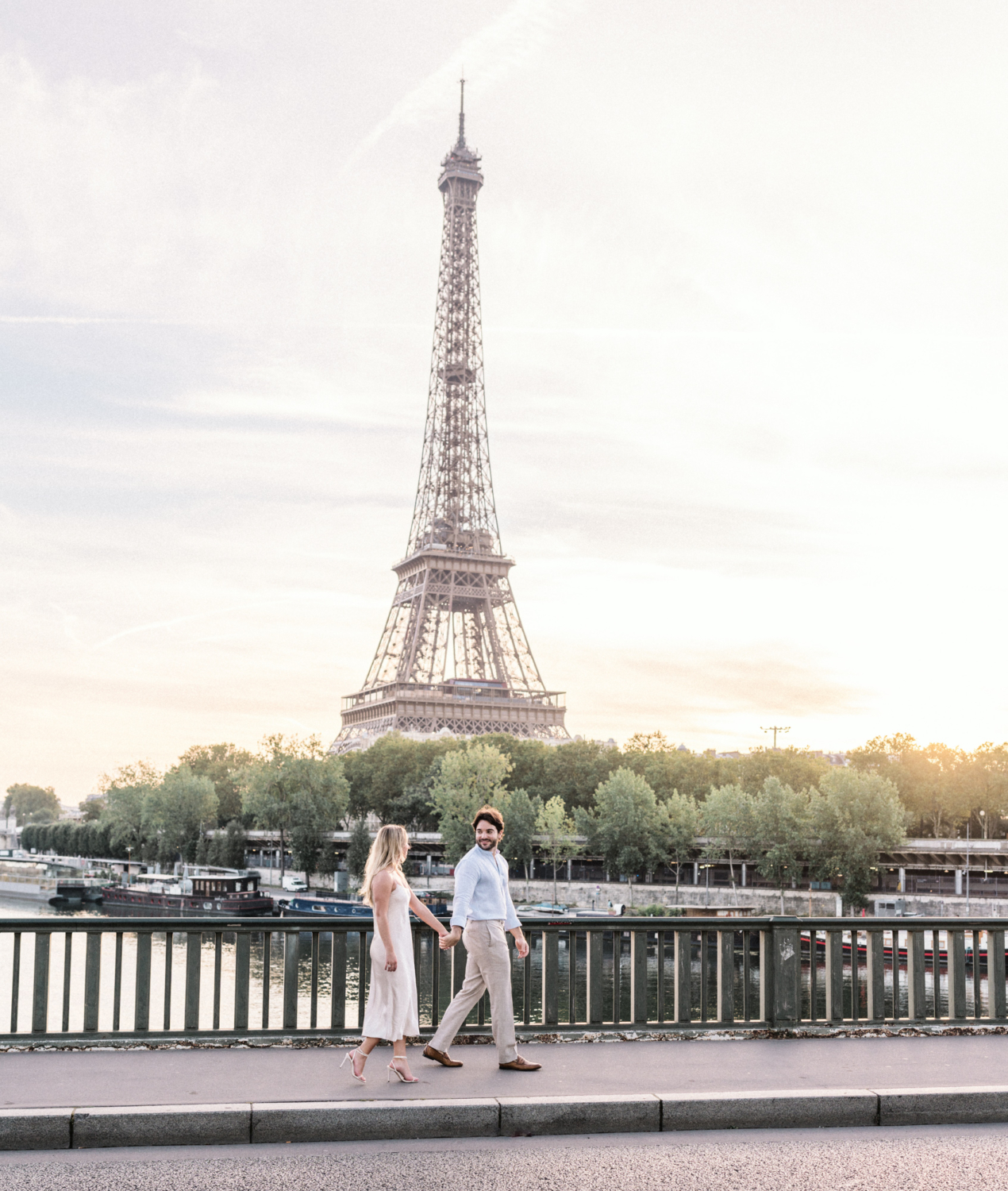 engaged young couple couple walk across bridge in paris