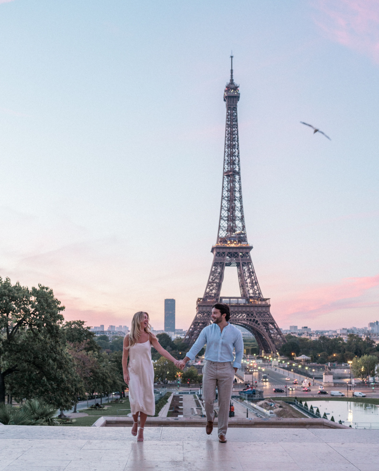 engaged young couple laugh at eiffel tower at sunrise in paris