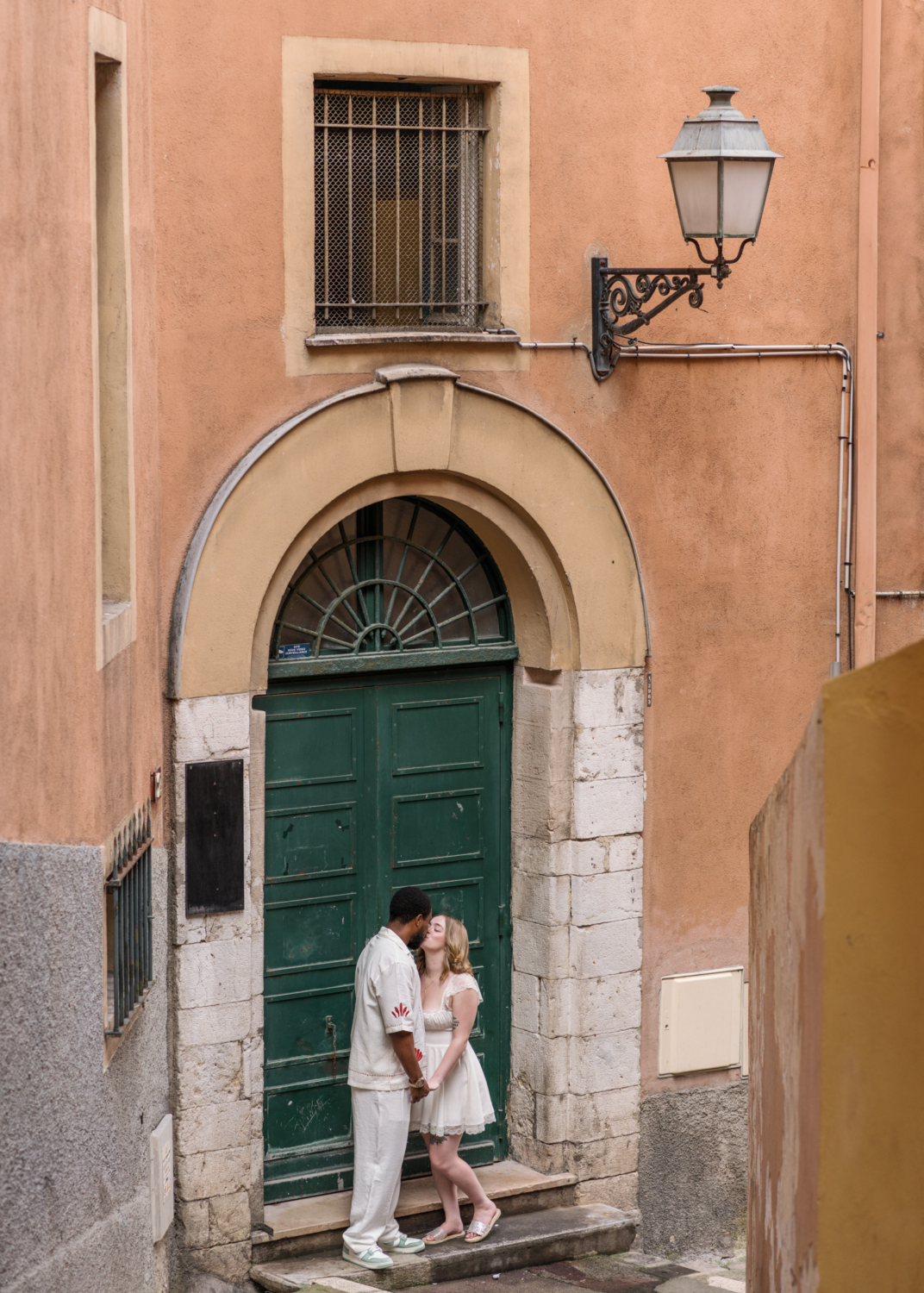 newlyweds kiss in front of green door in old nice france