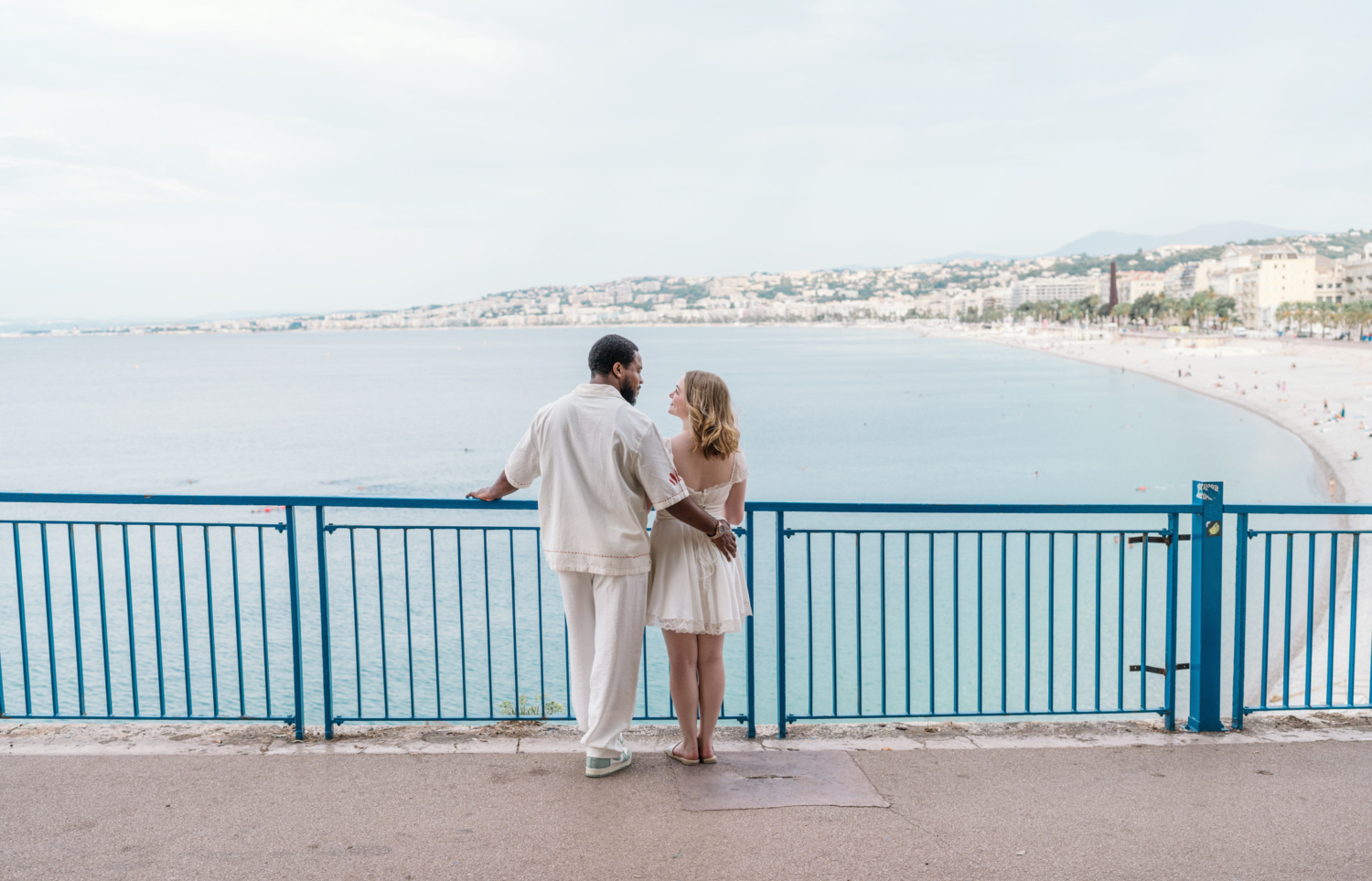 beautiful newlywed couple pose overlooking the sea in nice france