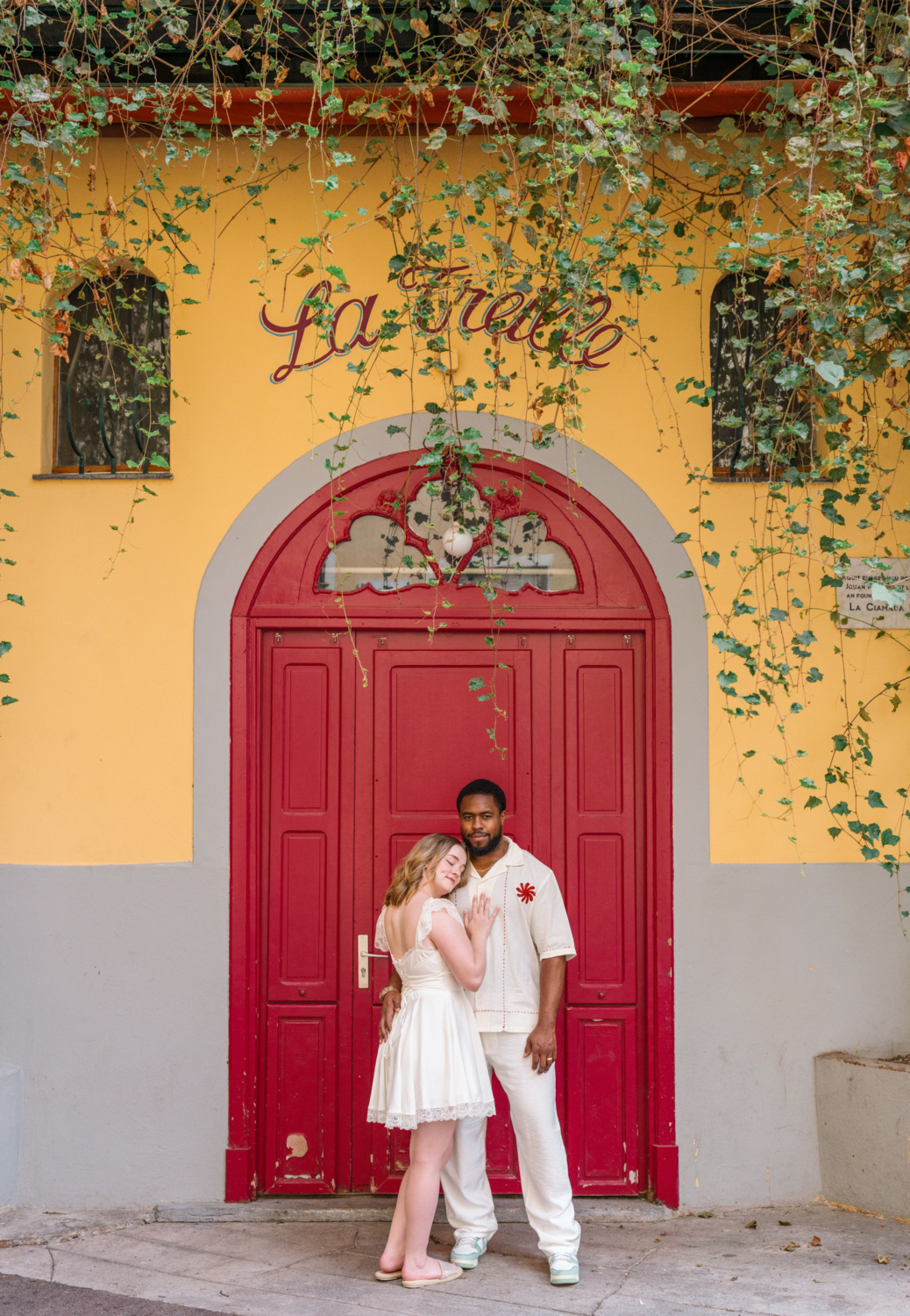 cute couple pose in front of red door in old town nice france