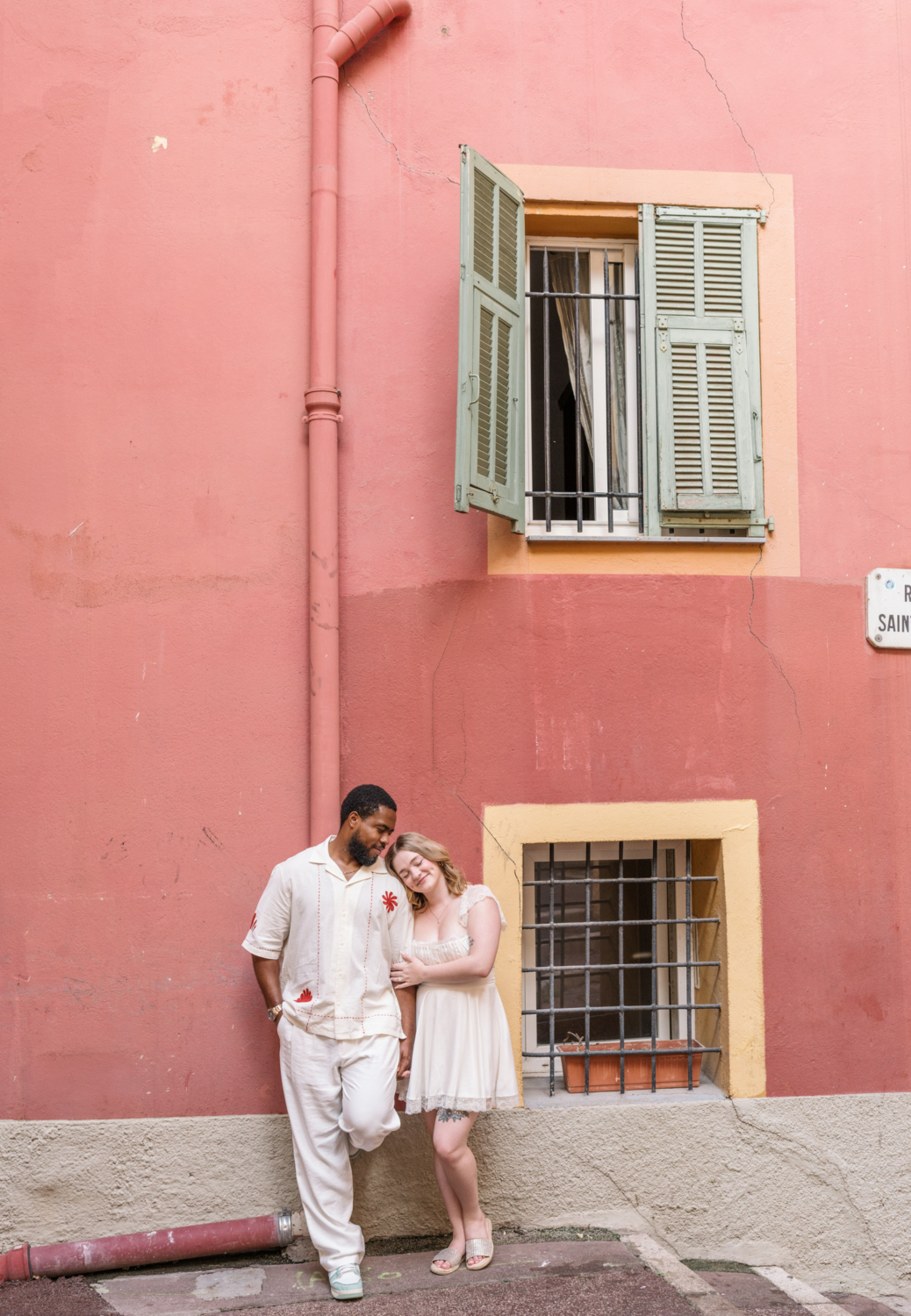 beautiful couple pose in front of orange building in old town nice