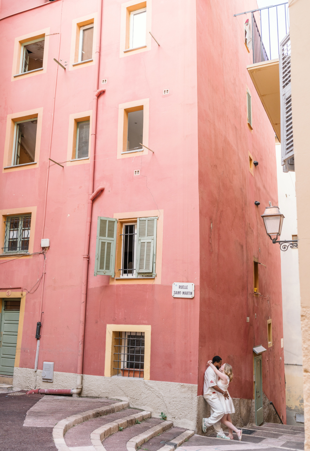 newlyweds embrace in front of pink building in old nice france