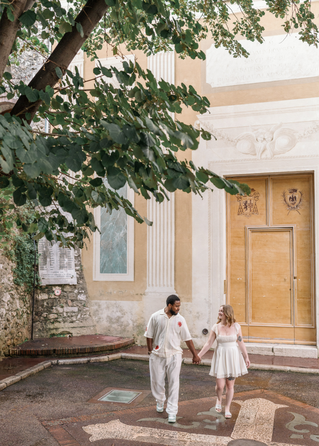 newlywed couple walk and laugh in old town nice in front of a church