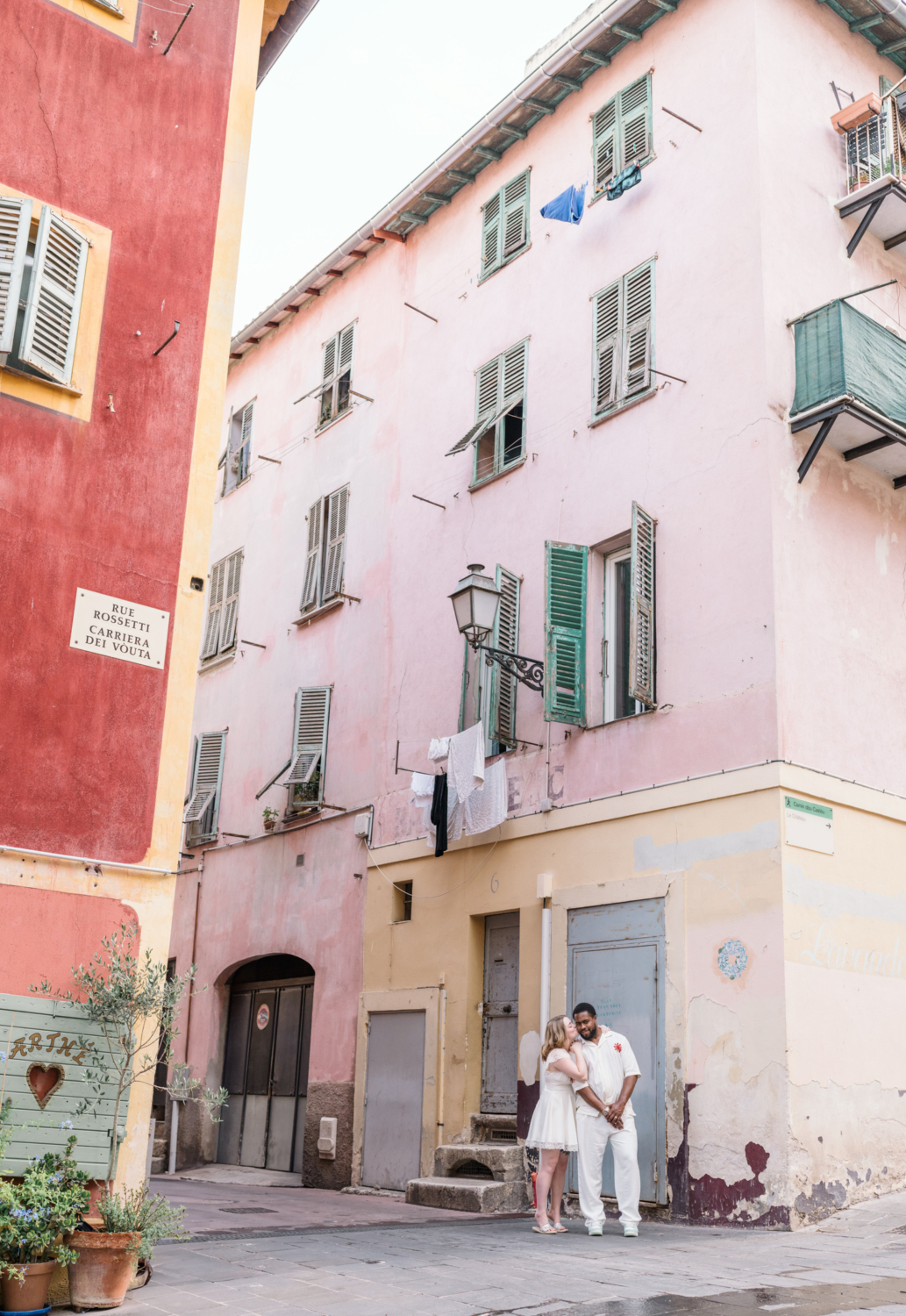 cute couple kiss in front of pink building in old nice france