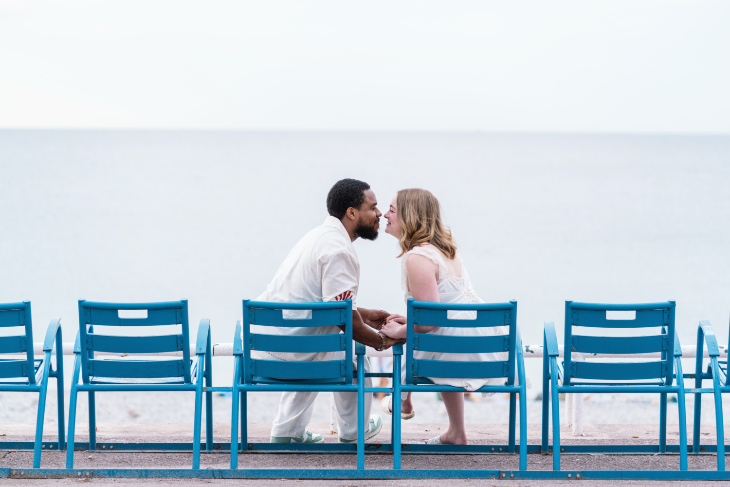 newlywed couple sit on famous blue beach chairs in nice france