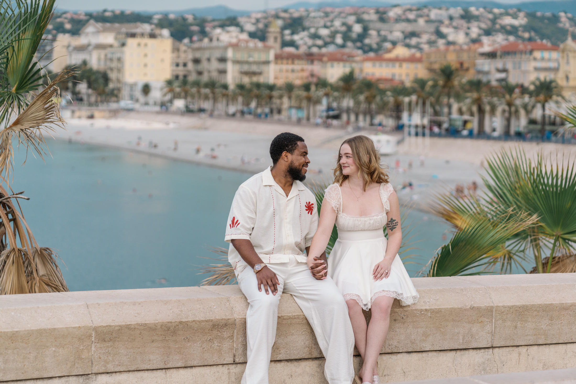 cute newlywed couple sit with view of nice france beach in background