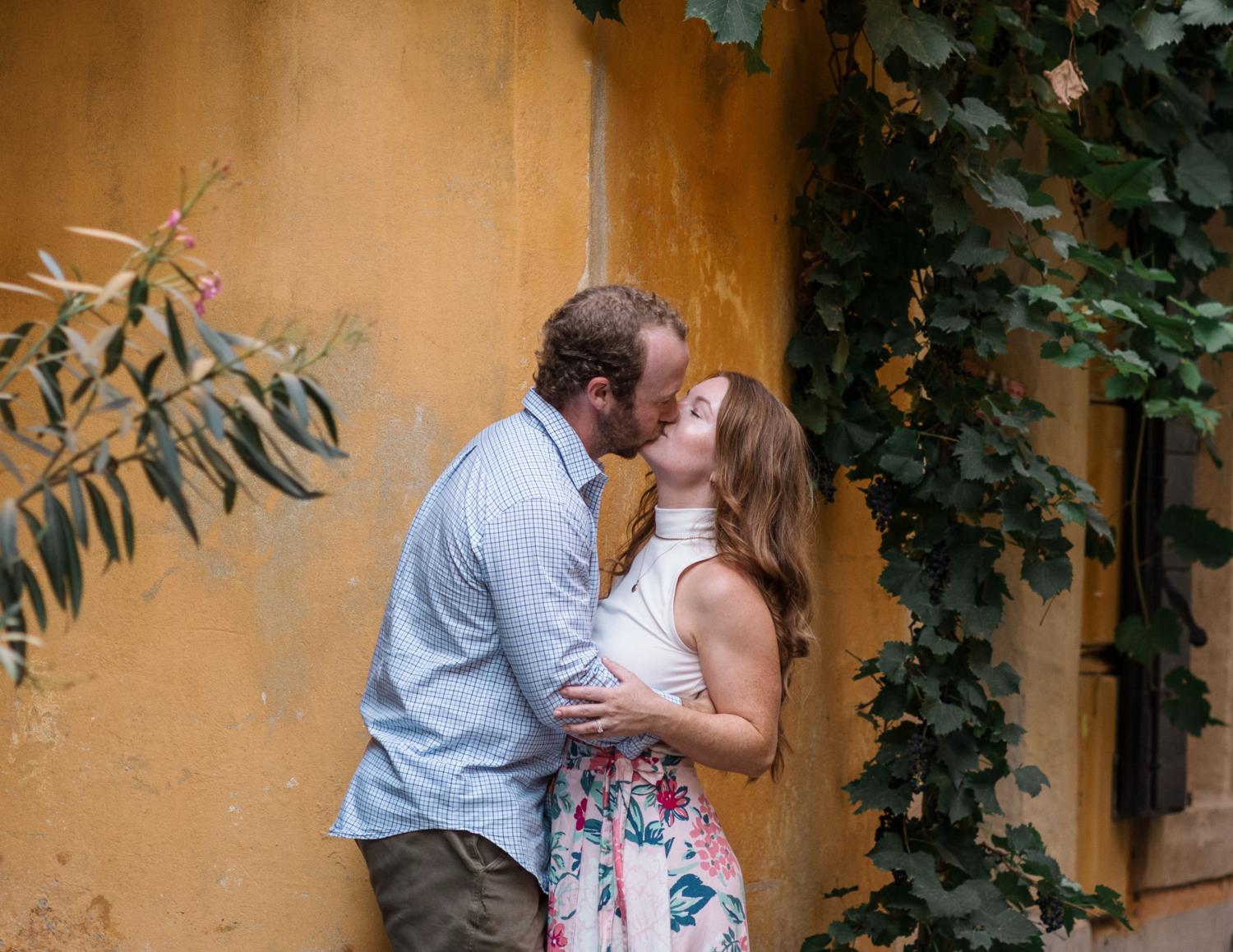 married couple kiss passionately in arles france next to yellow building