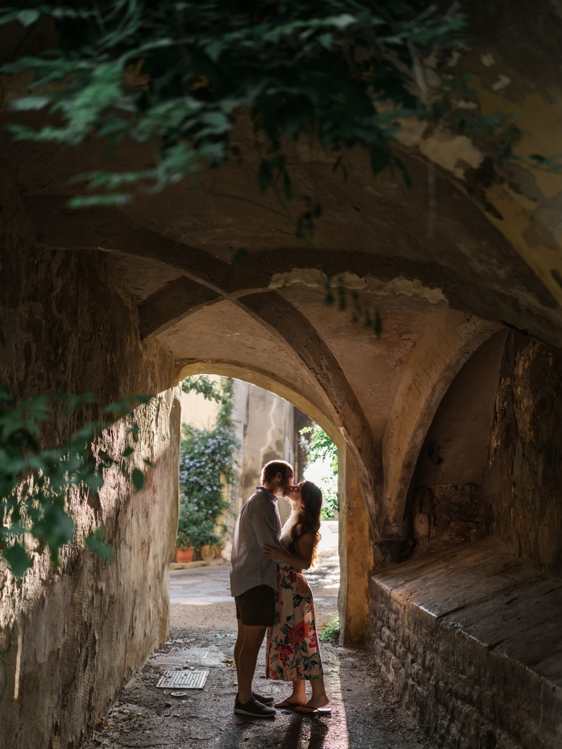 couple tenderly embrace and kiss under arch in romantic arles france