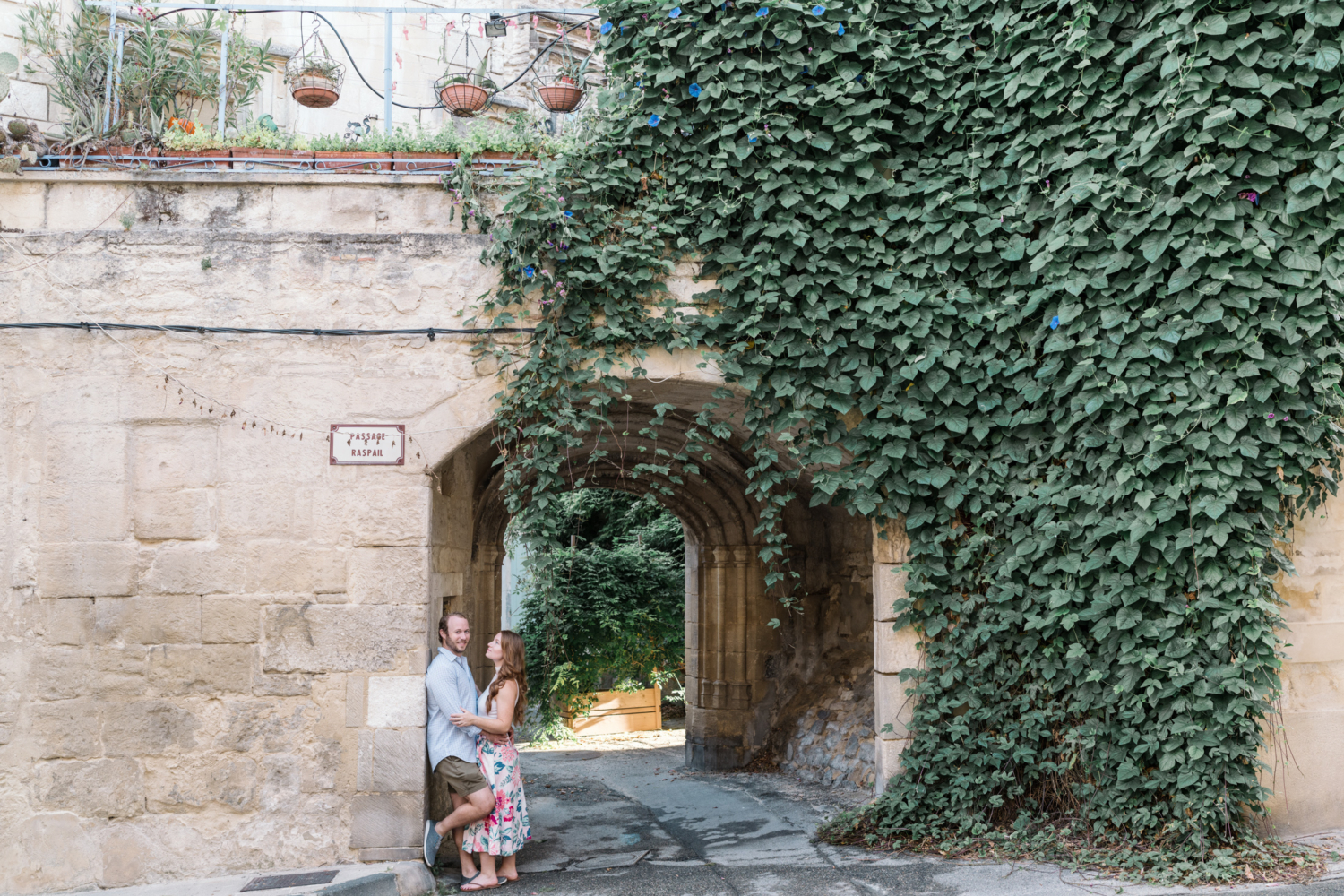 smiling man holds woman under medieval arch in arles france