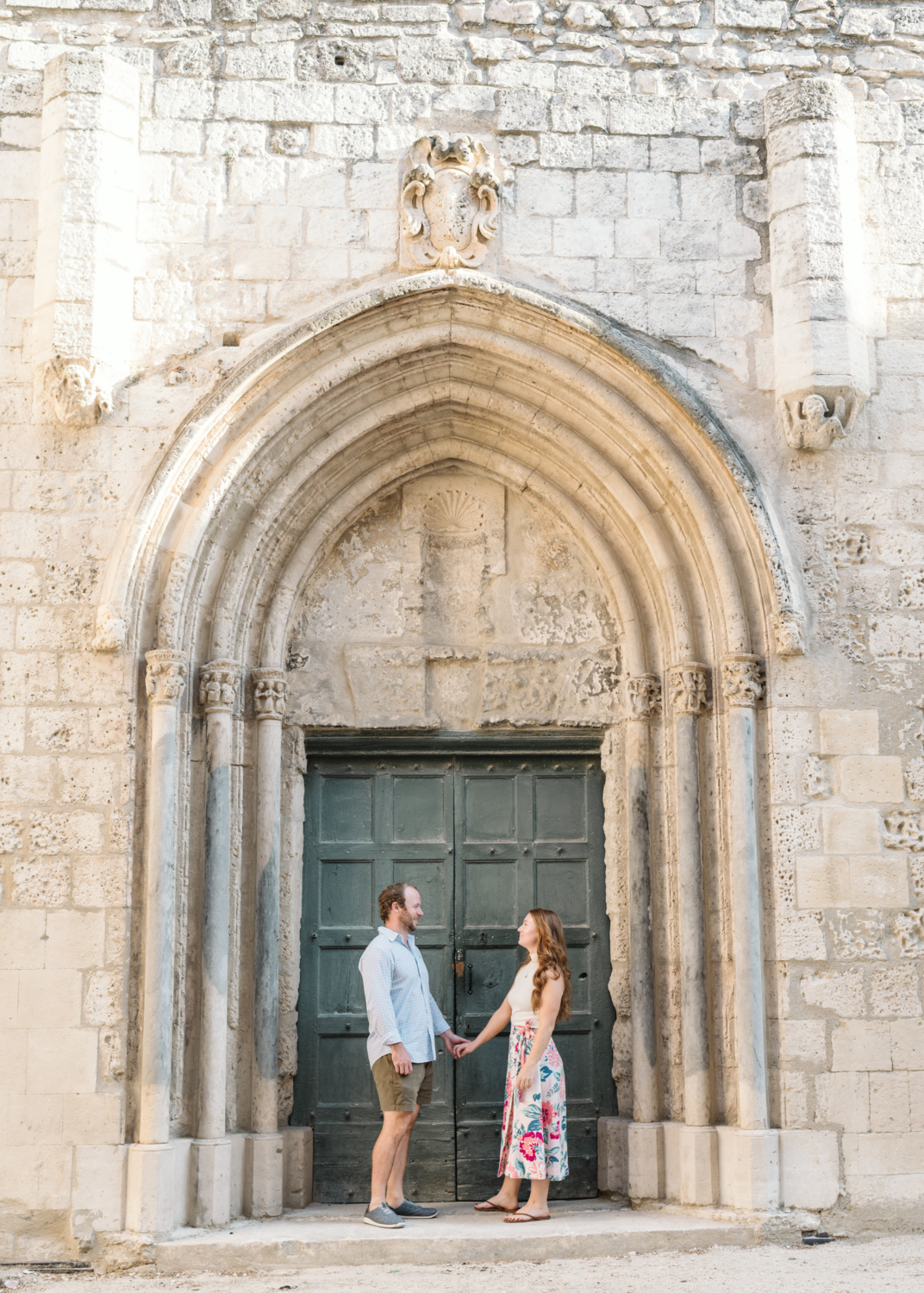 happy couple stand under medieval arch in arles france