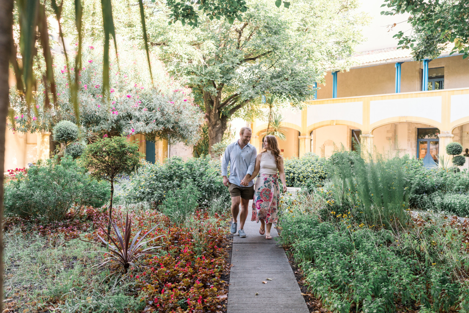 happy couple walk through beautiful garden in arles france