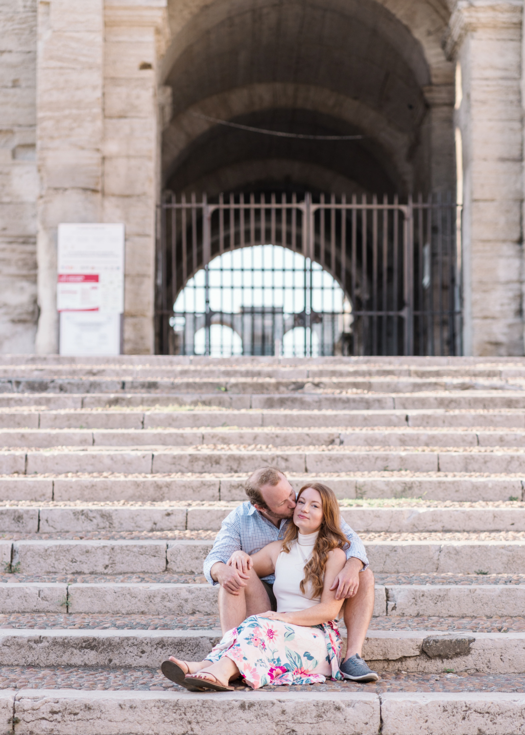 man kisses woman on cheek at roman amphitheater in arles france