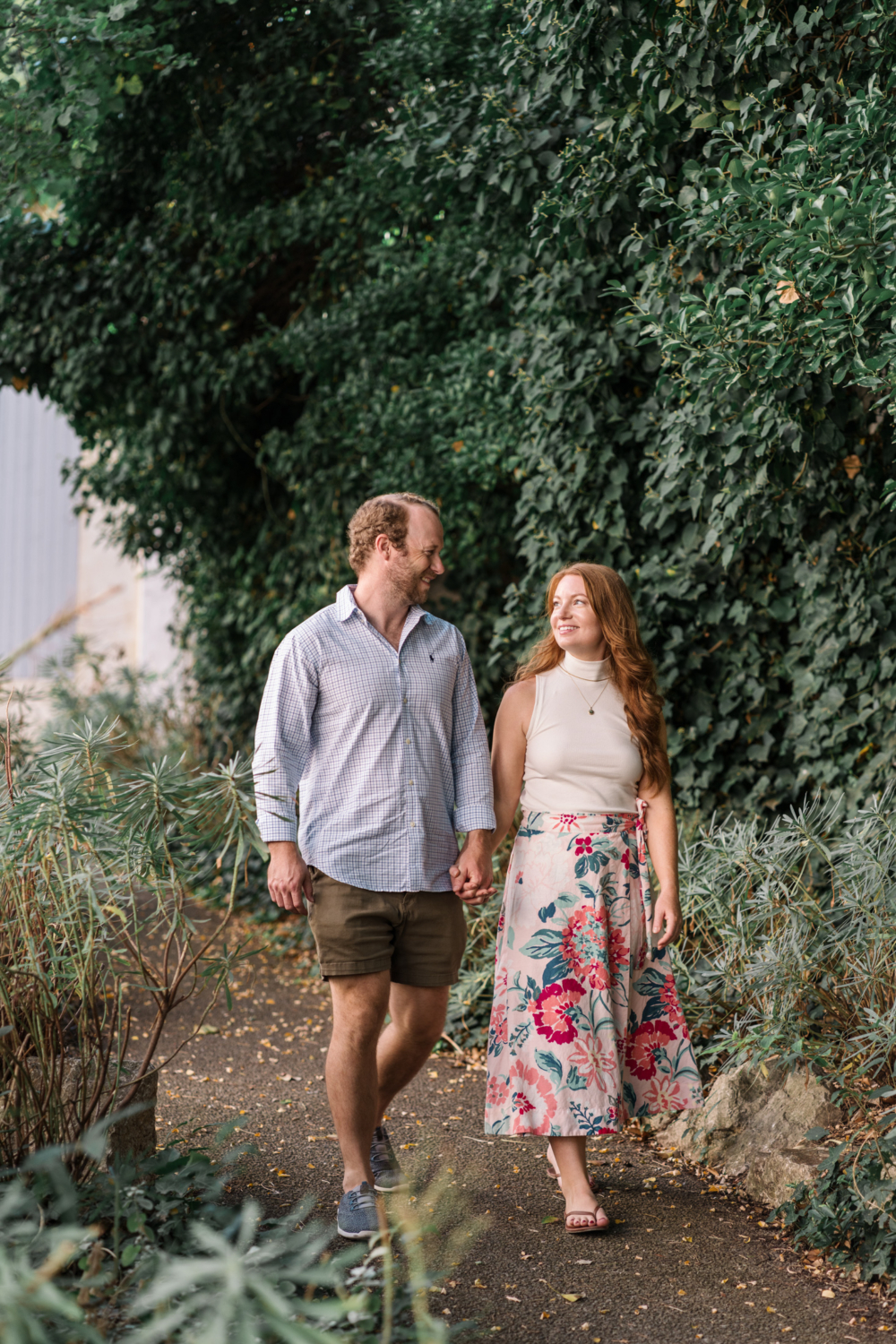 beautiful couple hold hands and walk through garden in arles france