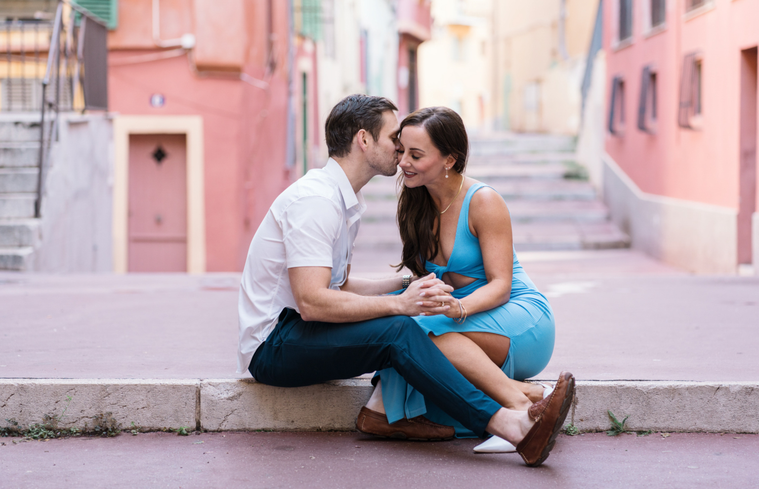 man tenderly kisses woman seated in the old town of nice france