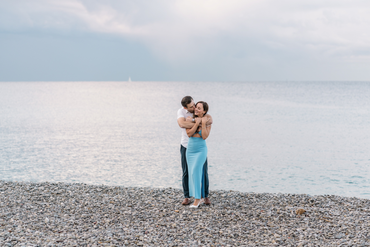 husband embraces and kisses wife on the beach in nice france