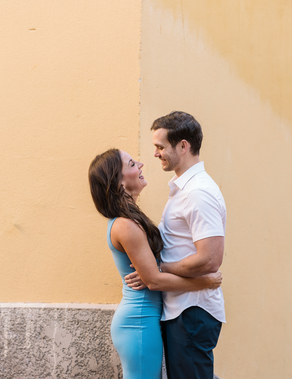 newlyweds laugh next to yellow building in old nice france