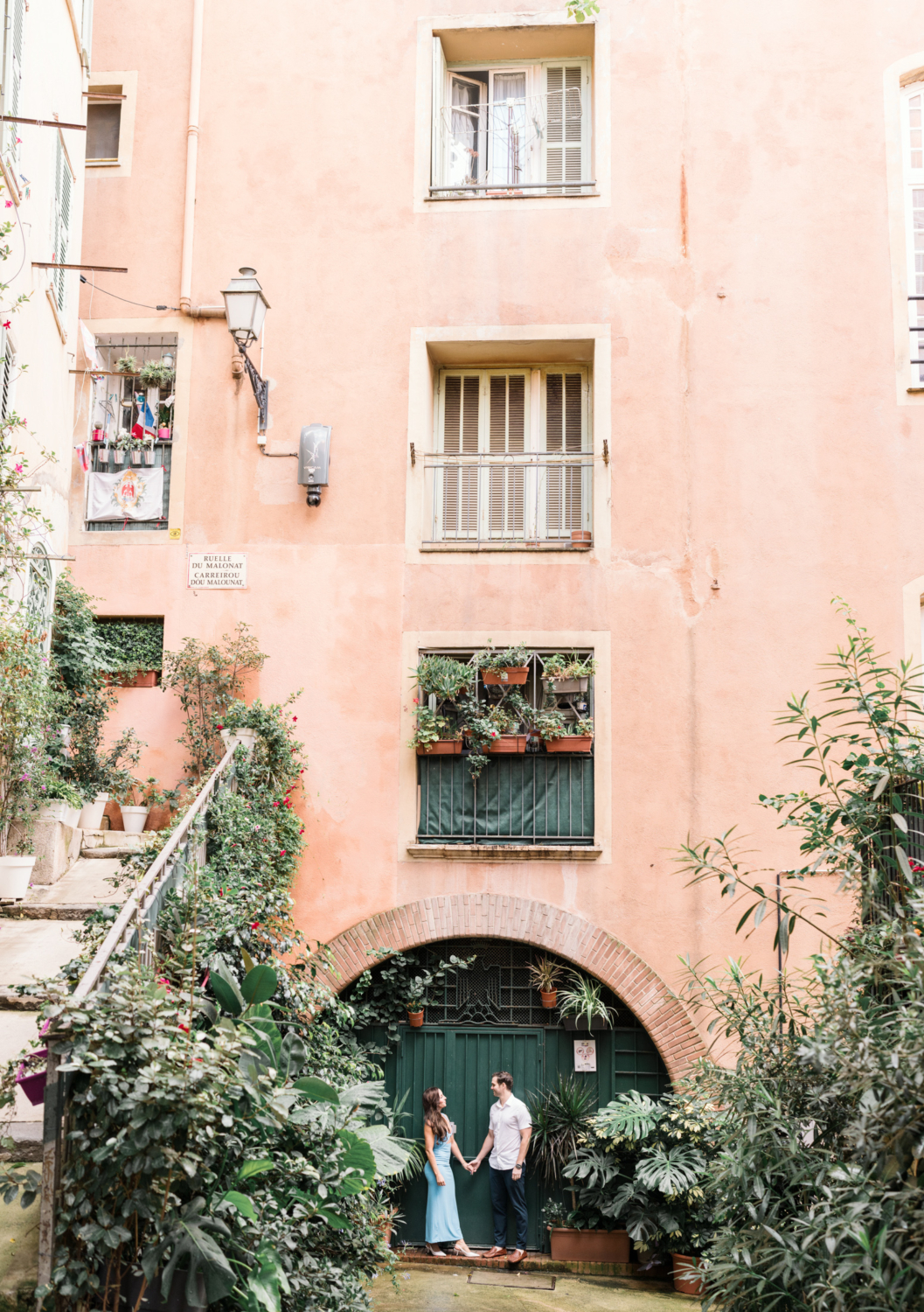 cute couple pose in front of green door in old town nice france