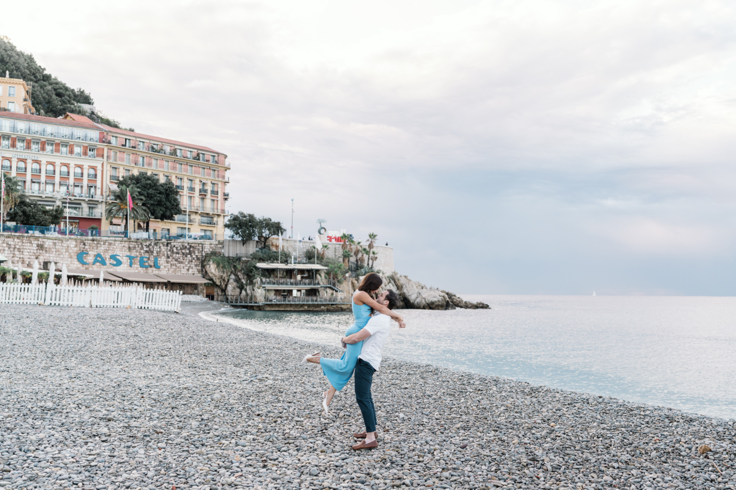 man lifts woman in air on beach in nice france