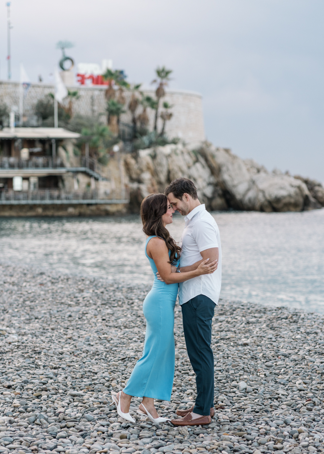 newlyweds embrace on beach in nice france with moody skies