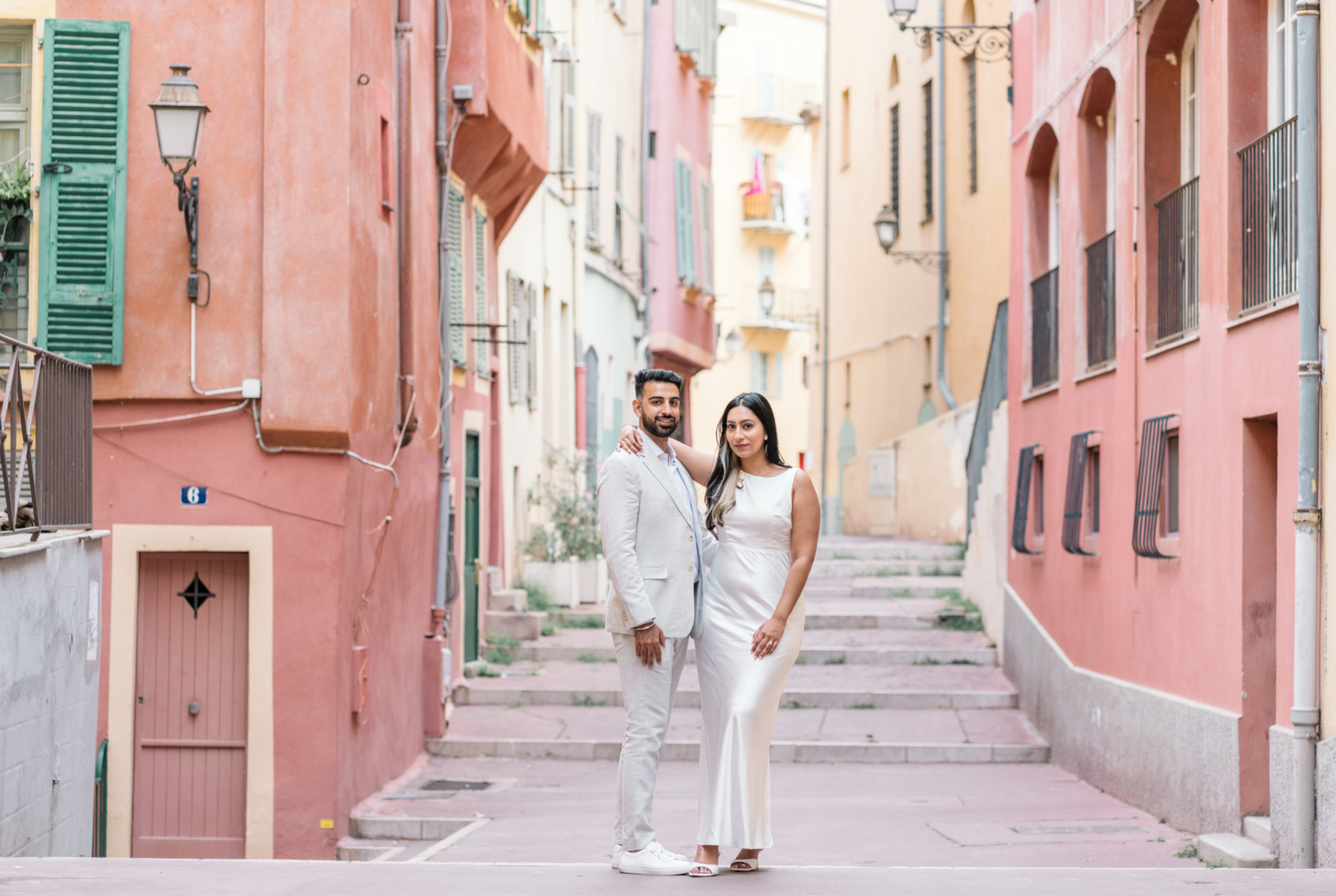 engaged indian couple pose behind colorful buildings in nice france