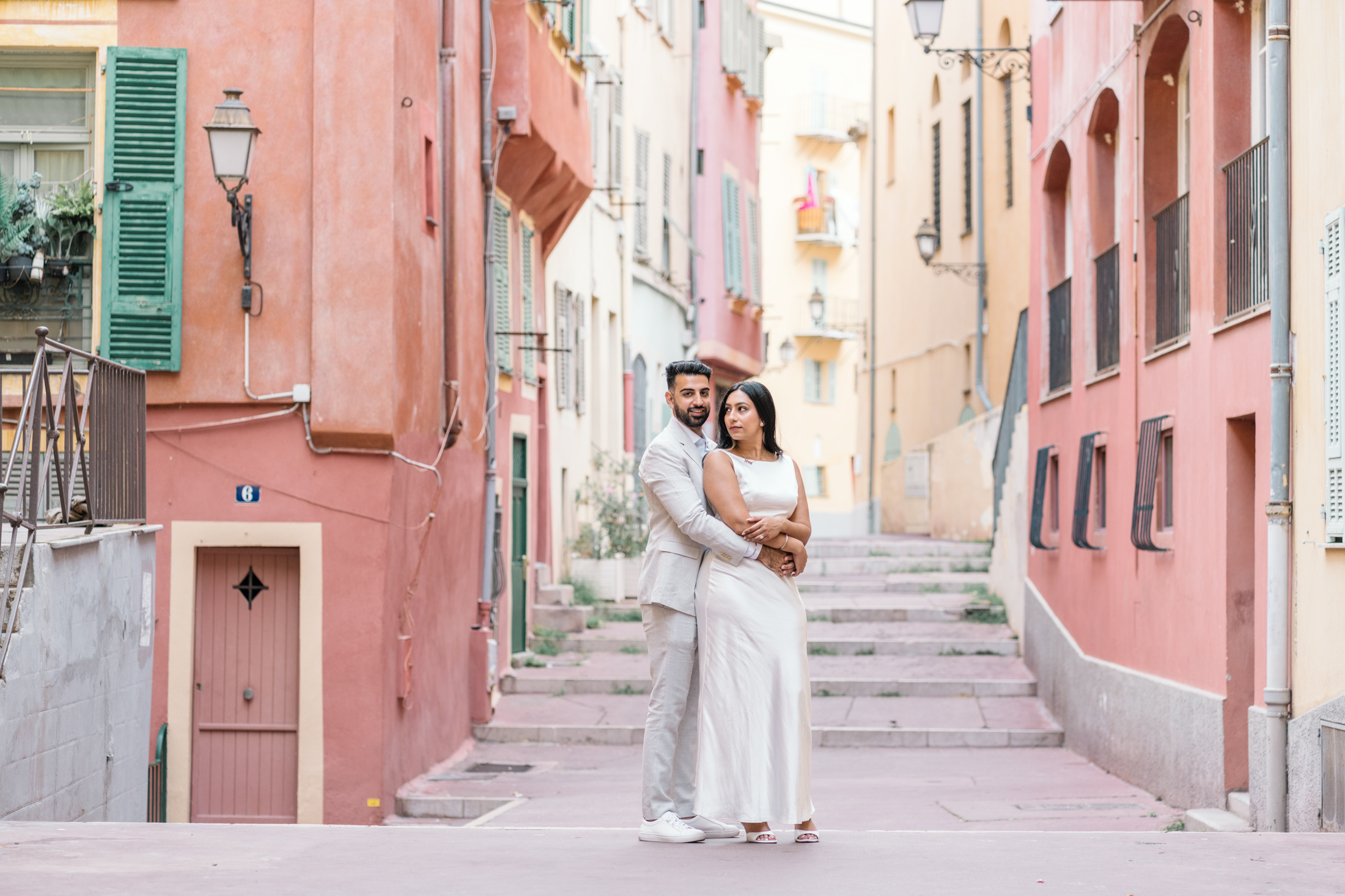 man smiles while holding his fiancee in old town nice france