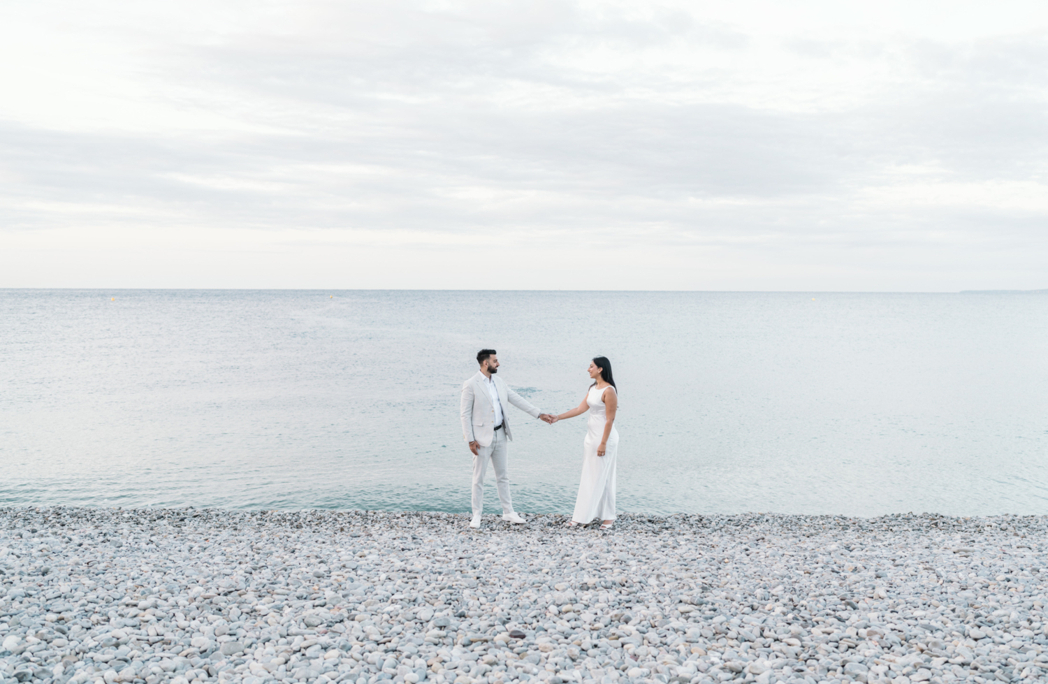 newly engaged couple hold hands next to the sea in nice france