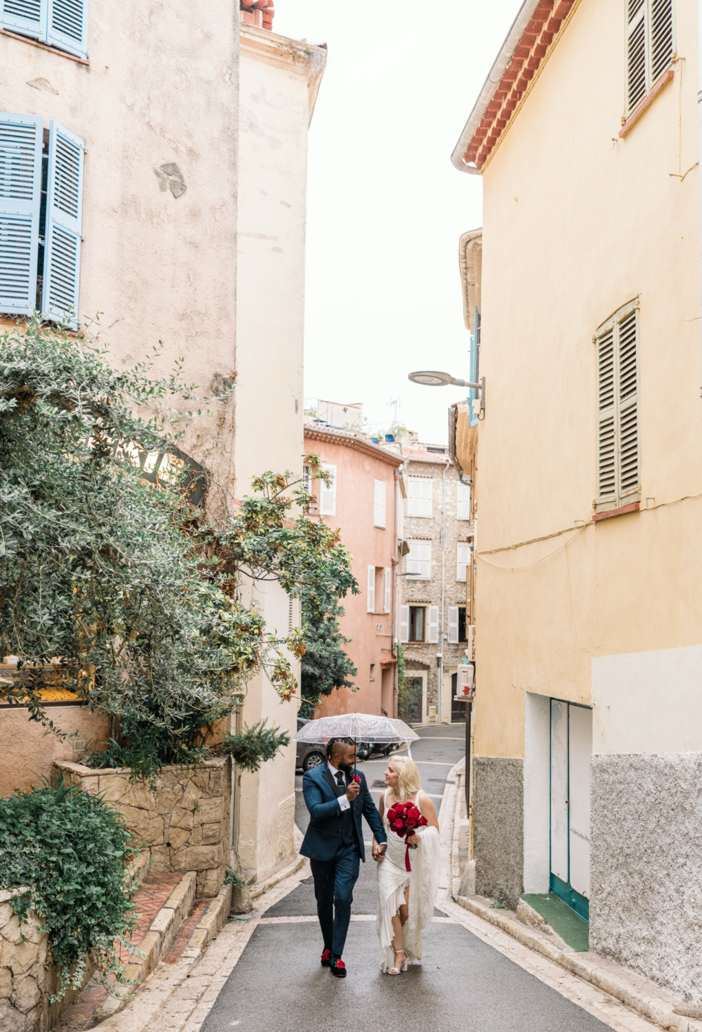 bride and groom walk streets of antibes france in the rain