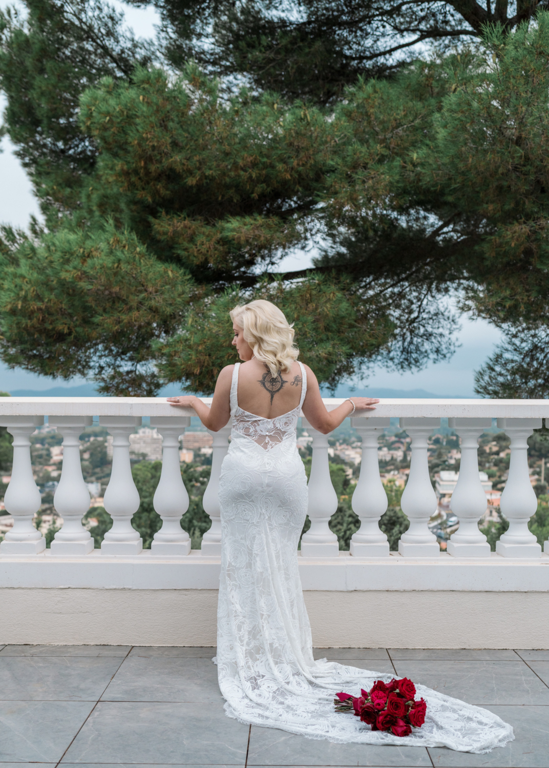 bride poses on balcony with bouquet of roses in antibes france