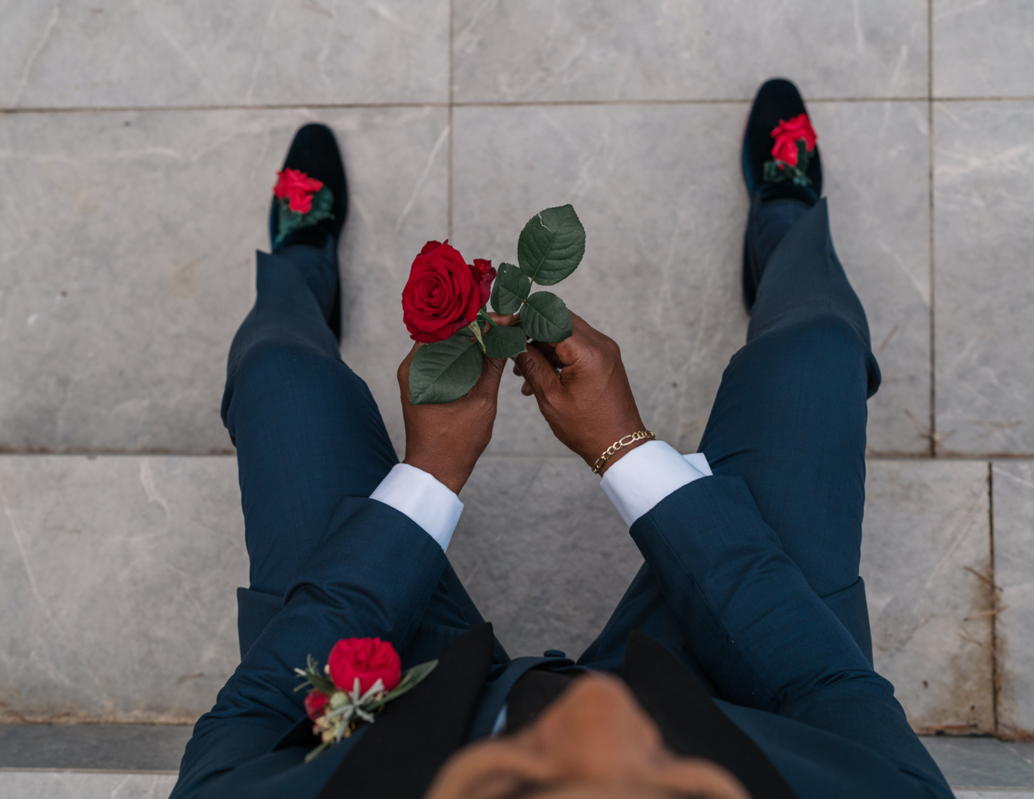 man holds rose and shows rose shows on his wedding day in antibes france