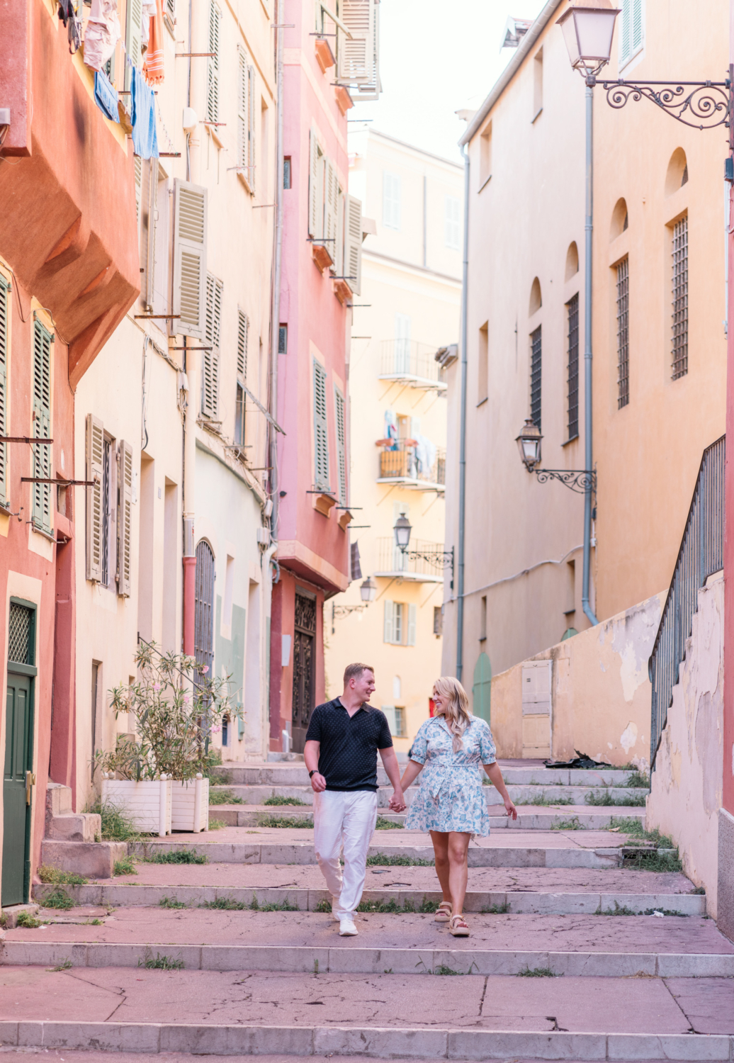 newly engaged couple hold hands walking around pastel buildings in old town nice